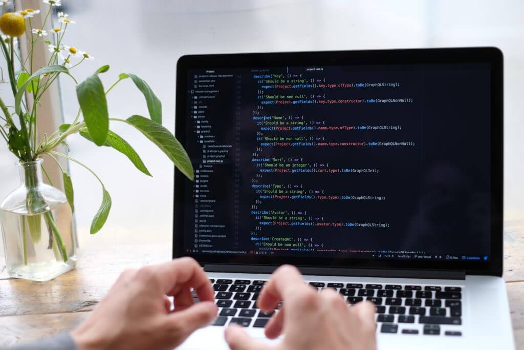 Photo of computer and programmer using Node.js for back-end development.